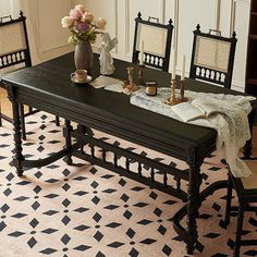 a dining room table with four chairs and a vase filled with flowers on top of it