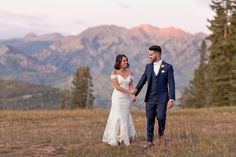 a bride and groom holding hands in the mountains