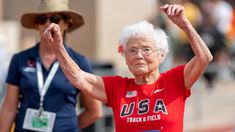 an older woman raises her arms as she crosses the finish line