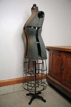 a mannequin sitting on top of a metal stand next to a wooden dresser