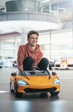 a man sitting on top of an orange sports car