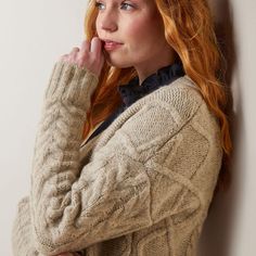 a woman leaning against a wall with her hand on her chin and looking off to the side