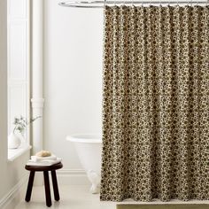 a bath room with a toilet and a shower curtain next to a tub in it