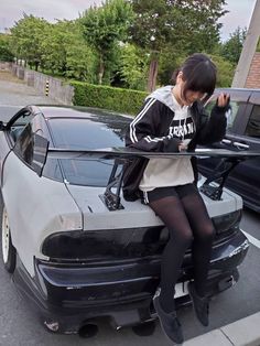 a woman sitting on the hood of a car