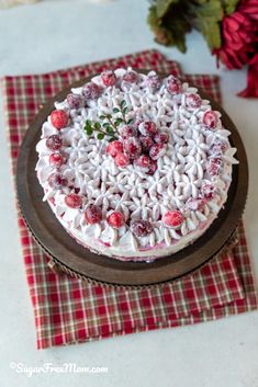 a cake with white frosting and cranberries on top sitting on a table