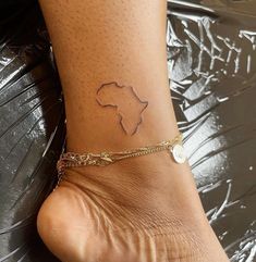 a woman's foot with a tattoo on the side of her leg and a gold chain around it