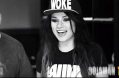 a woman wearing a black and white hat with the words woke on it, standing next to a man