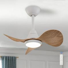 a white ceiling fan with wooden blades in a room