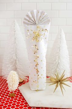 a white vase sitting on top of a table next to christmas trees