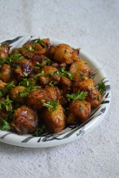 a white plate topped with fried food and garnished with parsley on top