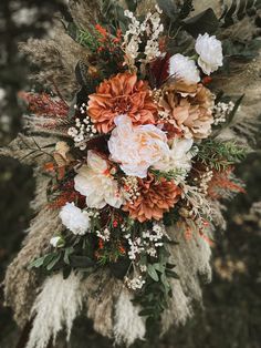 an arrangement of flowers and greenery hanging from a tree