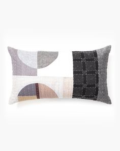 a gray and white pillow with geometric shapes on the front, along with a black and white background