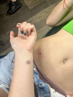 a woman with a small star tattoo on her left arm and right hand behind her belly