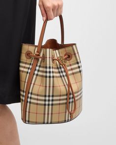 Burberry bucket bag in check faux leather (polyurethane), polyester, cotton, and leather     Features a Thomas Burberry monogram    Top handle     Detachable, adjustable crossbody strap    Can be worn as a top handle or crossbody bag     Drawstring closure     Lining: Cotton    Approx. 6.3"H x 10.2"W x 10.2"D    Made in Italy Burberry Bucket Bag, Burberry Monogram, Thomas Burberry, Drawstring Bucket Bag, Bed Stu, Burberry Handbags, Nylon Bag, Goodie Bags, Burberry Bag