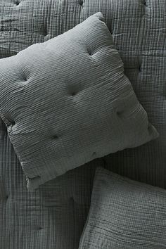 two gray pillows sitting on top of a couch