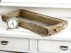 an old wooden box with a clock sitting on it's side shelf next to drawers