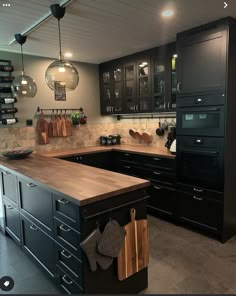 a kitchen with black cabinets and wooden counter tops, hanging lights above the sink and oven