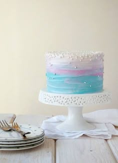 a cake sitting on top of a wooden table next to plates and silverware in front of a white wall