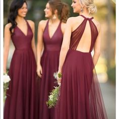 three bridesmaids in maroon dresses standing together and looking at each other with their backs to the camera