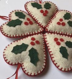 four felt ornaments with holly and berries on them