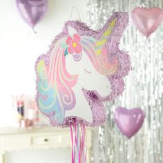 a pink and purple unicorn pinata with hearts hanging from it's sides on a table