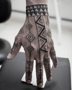 a person's hand with black and white tattoos on it, sitting on top of a table