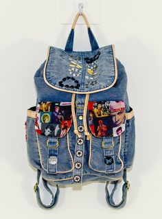 a blue backpack with mickey mouse patches on the front and back straps, hanging from a hook