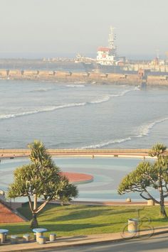 a view of the ocean from an apartment building in front of some trees and buildings