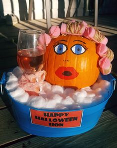 a pumpkin in a bucket with marshmallows around it and a glass of wine