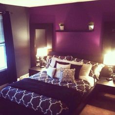 a bedroom with purple walls, black and white bedspread, two lamps on either side of the bed