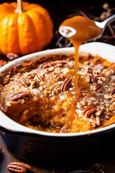 a spoon drizzling caramel sauce onto a baked pumpkin casserole