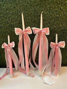 three candles with pink ribbons tied around them