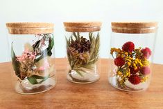 three glass jars filled with different types of flowers