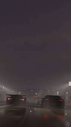 two cars driving down the road at night with lights on and fog in the air