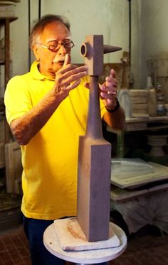 an older man is making a sculpture out of wood