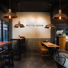 an empty restaurant with wooden tables and stools in front of the wall that says eating space