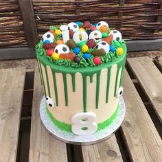 a birthday cake decorated with soccer balls and sprinkles on a wooden table