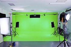 a green screen is set up in an empty room with lights and lighting equipment on the floor