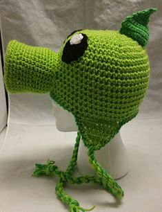 a crocheted green bird hat with black eyes