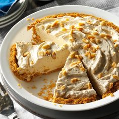 a white plate topped with a cheesecake covered in frosting and chopped walnuts