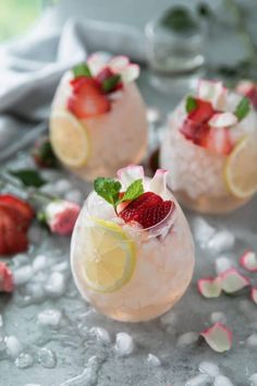 two glasses filled with lemonade and strawberries on top of ice next to sliced strawberries