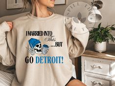 a woman wearing a sweatshirt that says i married no one but go detroit