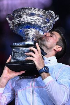 a tennis player kissing the trophy he won