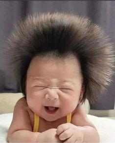 a baby with a mohawk on top of it's head laying on a bed