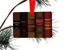 a book ornament hanging from a christmas tree branch with five books on it