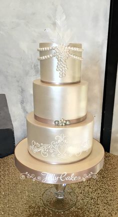 a three tiered wedding cake with pearls on the top and ribbon at the bottom