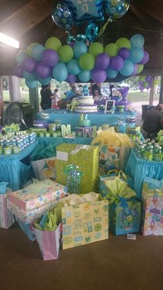 a table filled with lots of presents under balloons