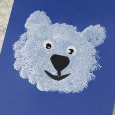 a polar bear made out of white powder on a blue paper with eyes and nose