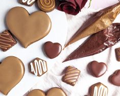 chocolates are arranged in the shape of hearts on a white tablecloth next to flowers