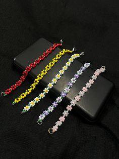 four bracelets with flowers on them sitting next to each other in front of a black background